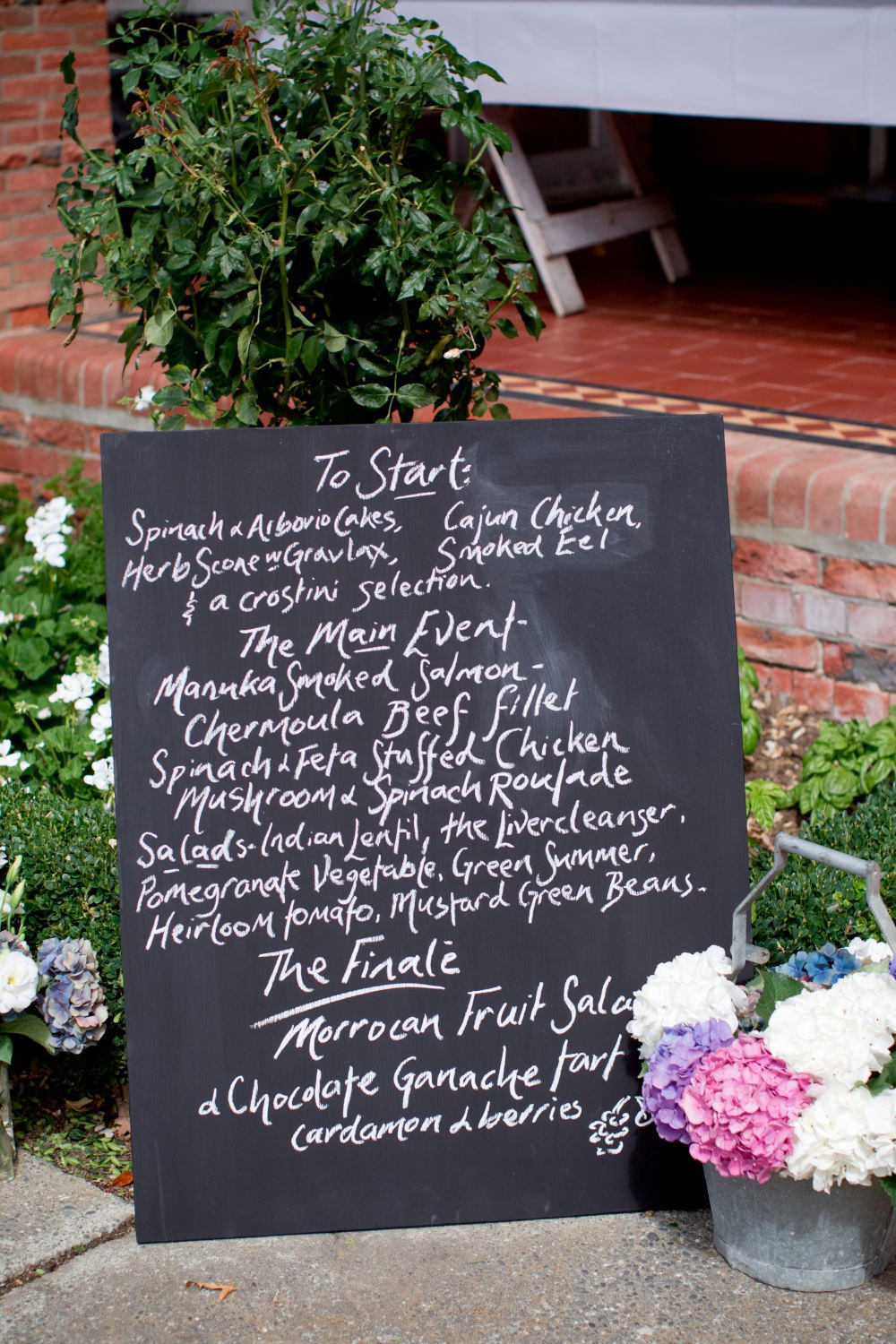 A chalk menu board set among flowers outside