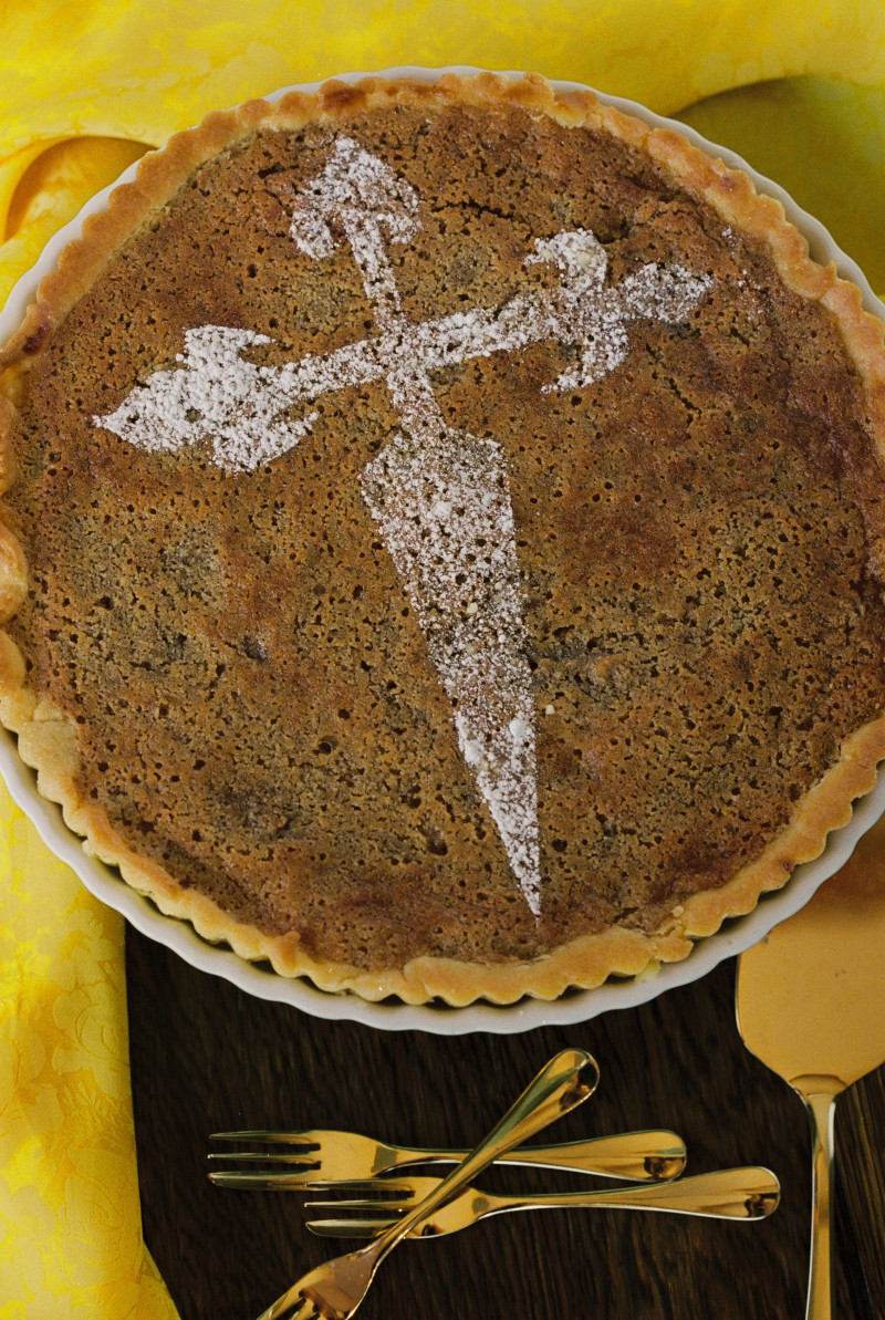 A brown tart with an ornate cross pattern on a table